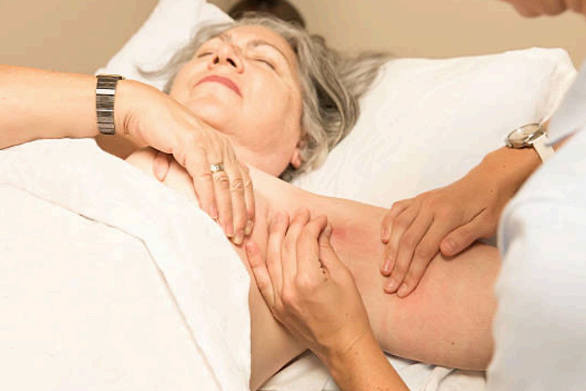 a woman is lying in a bed getting a massage from a nurse
