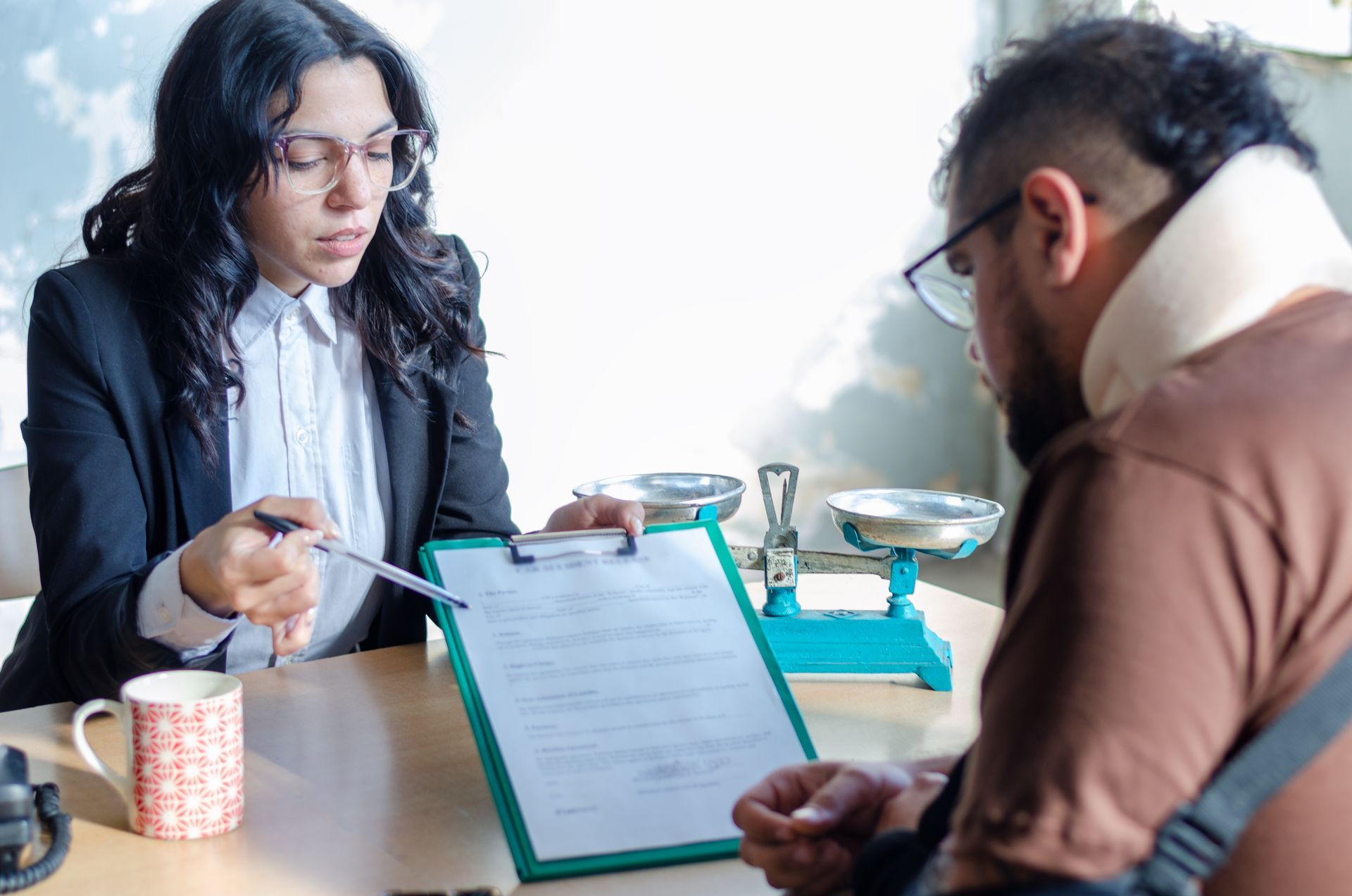 Two people in a clinic discussing paperwork across a table with medical tools and forms.