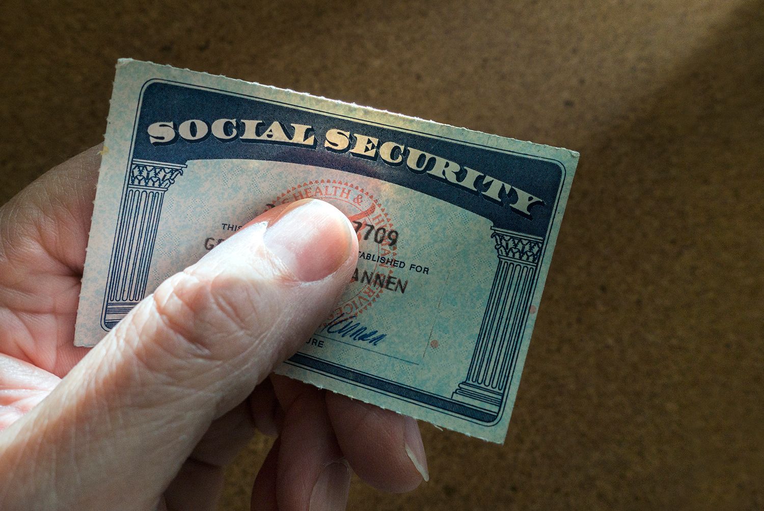 Hand holding a Social Security card over a neutral background. Hand holding a Social Security card over a neutral background.