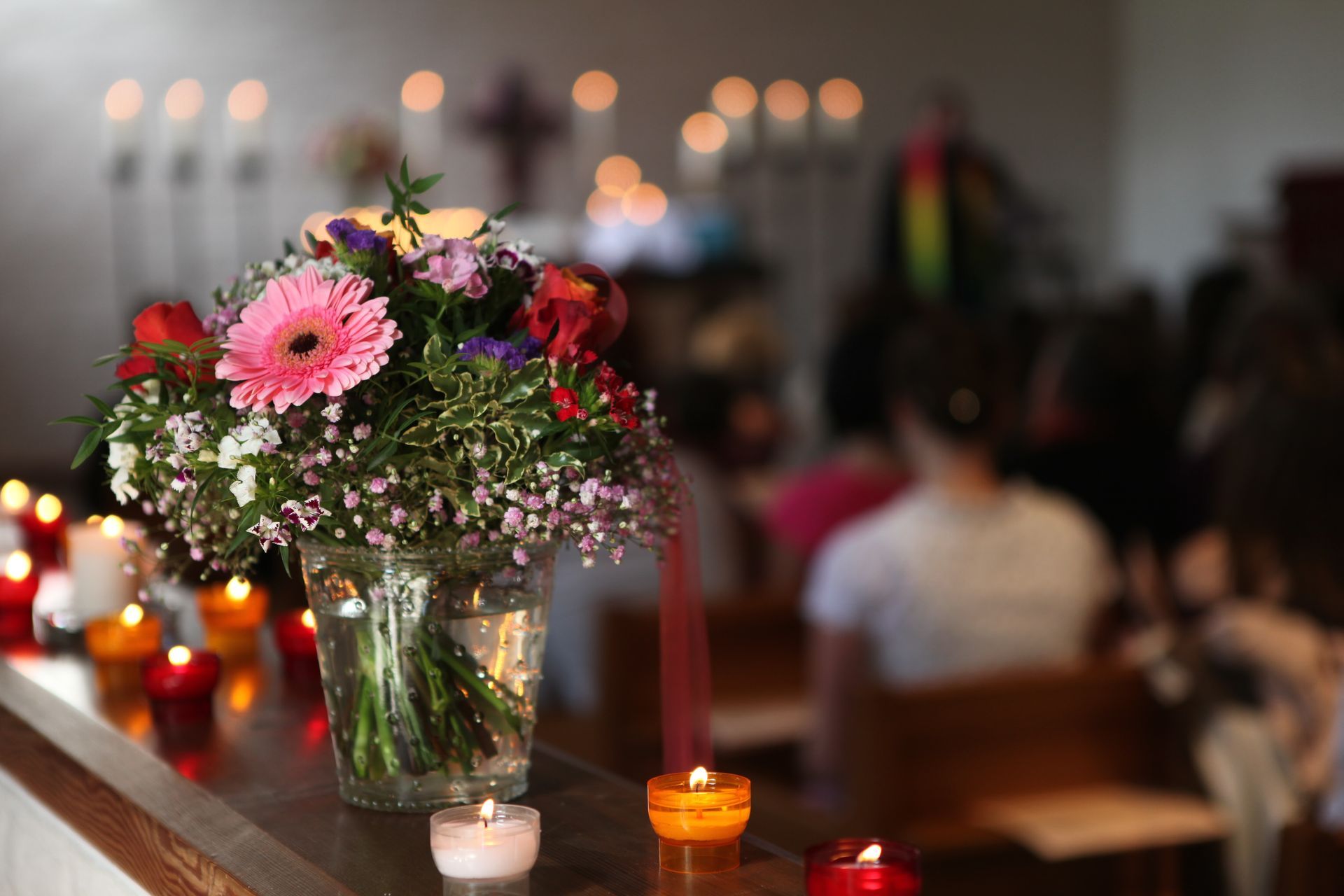 Flower arrangement with candles on a table in a softly lit church or ceremony setting