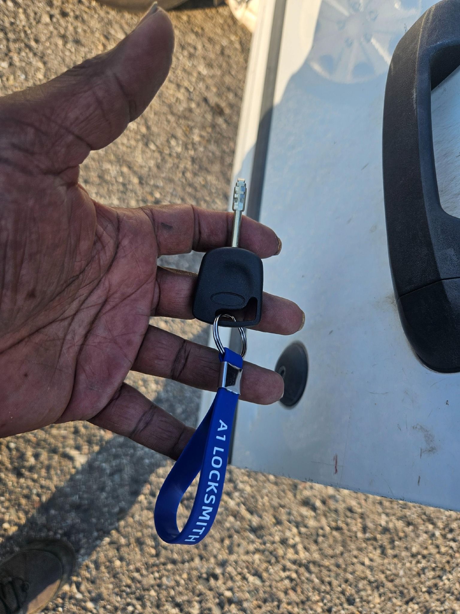 Hand holding a car key with a blue 