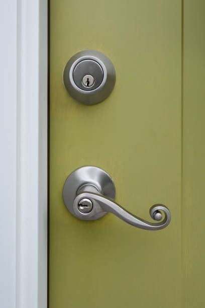 Silver doorknob and deadbolt on a light green door; white door frame.