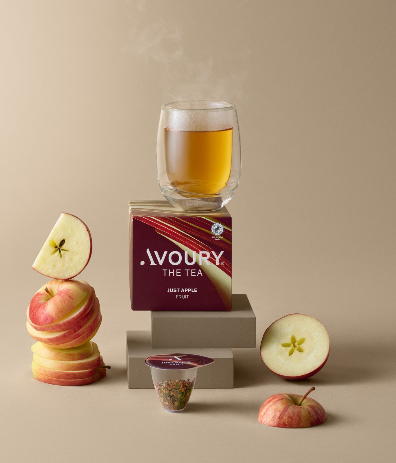 Apple tea product display with sliced apples and a glass cup on stacked boxes