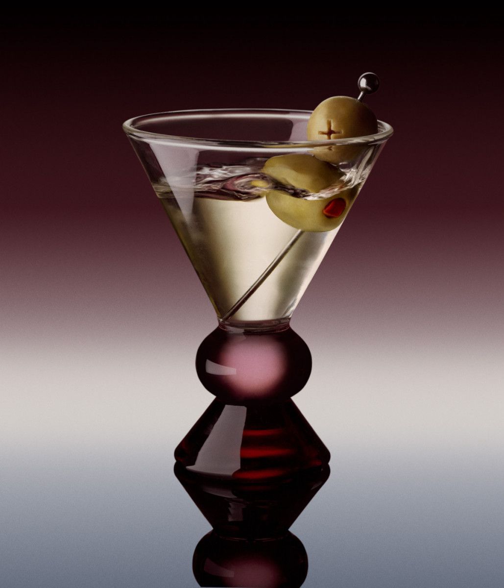 Martini glass with two green olives on a skewer, set against a dark gradient background