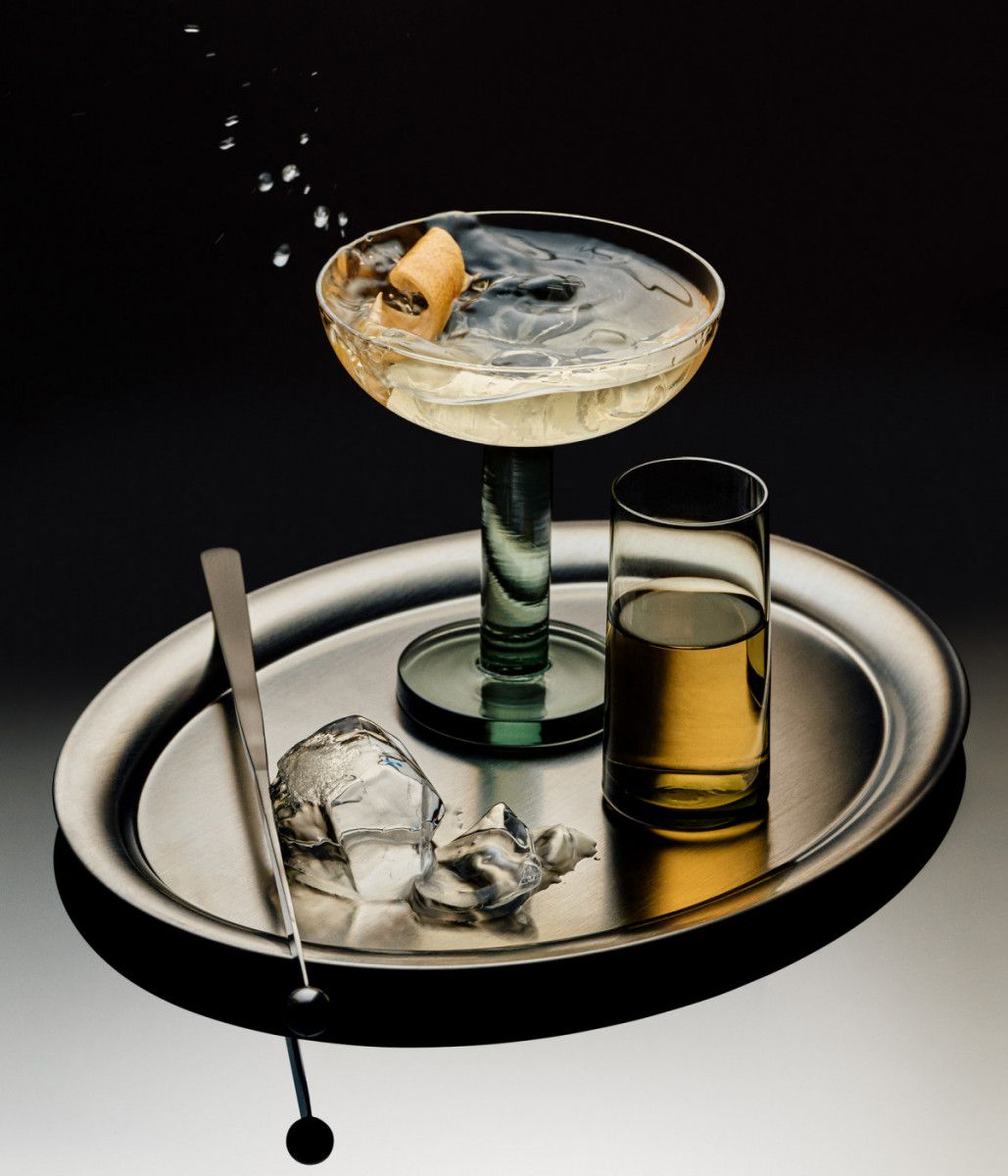 Cocktail tray with martini, whiskey glass, ice cubes, and lemon on a silver serving tray