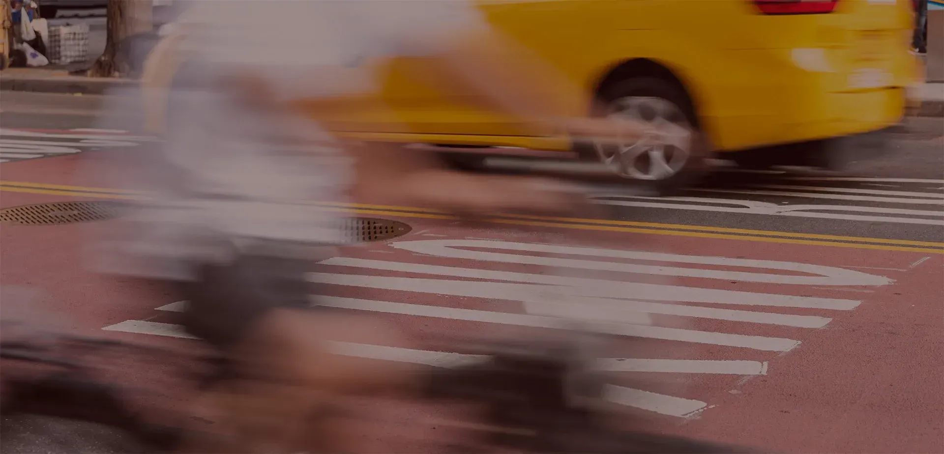A cyclist on a bicycle and a car speed in opposite directions in a busy street