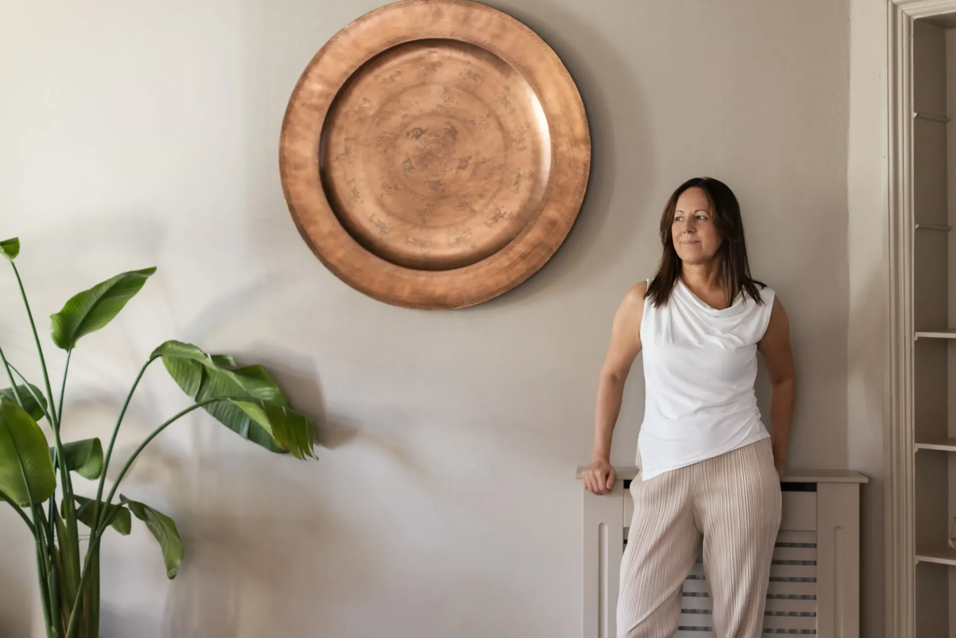 a woman stands in front of a large copper plate on the wall