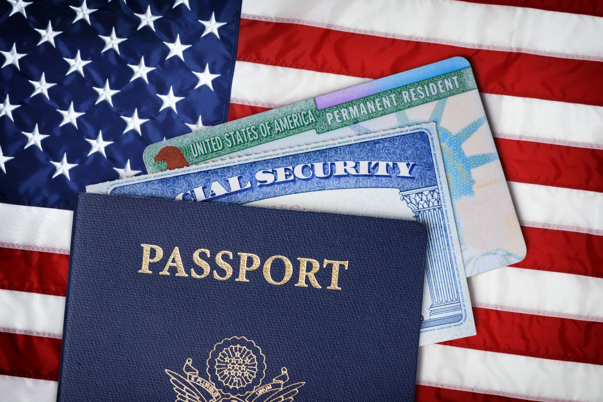 Passport, Social Security card, and green card against American flag.
