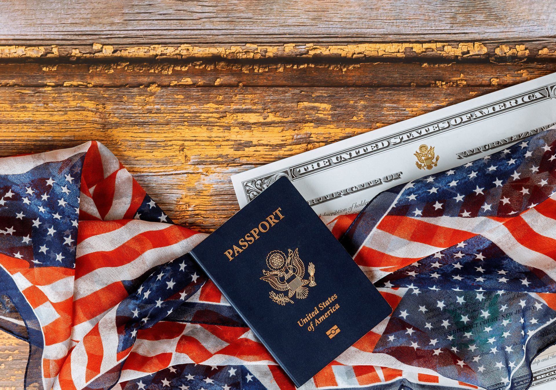 U.S. passport on an American flag beside a form, on a wooden table