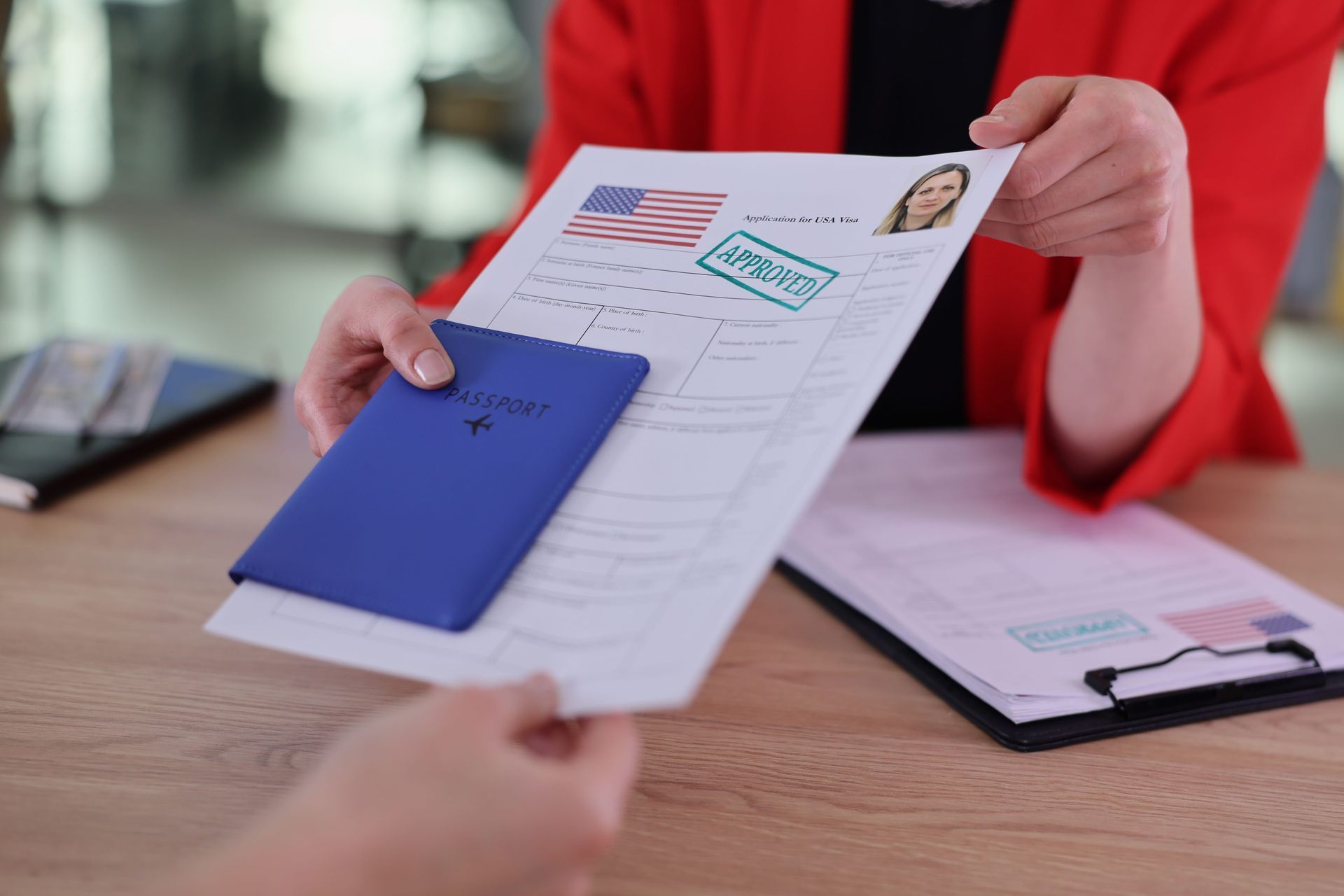 Hands exchanging a passport and documents across a desk during an interview.