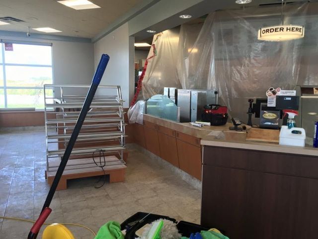 Shuttered restaurant counter area with sanitizer station, stacked trays, and a mop in the foreground