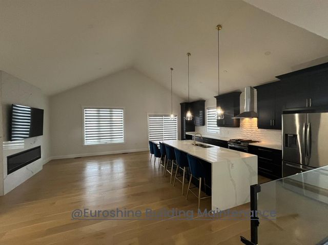 Open-concept kitchen and living room with dark cabinets, white island, and hardwood floors