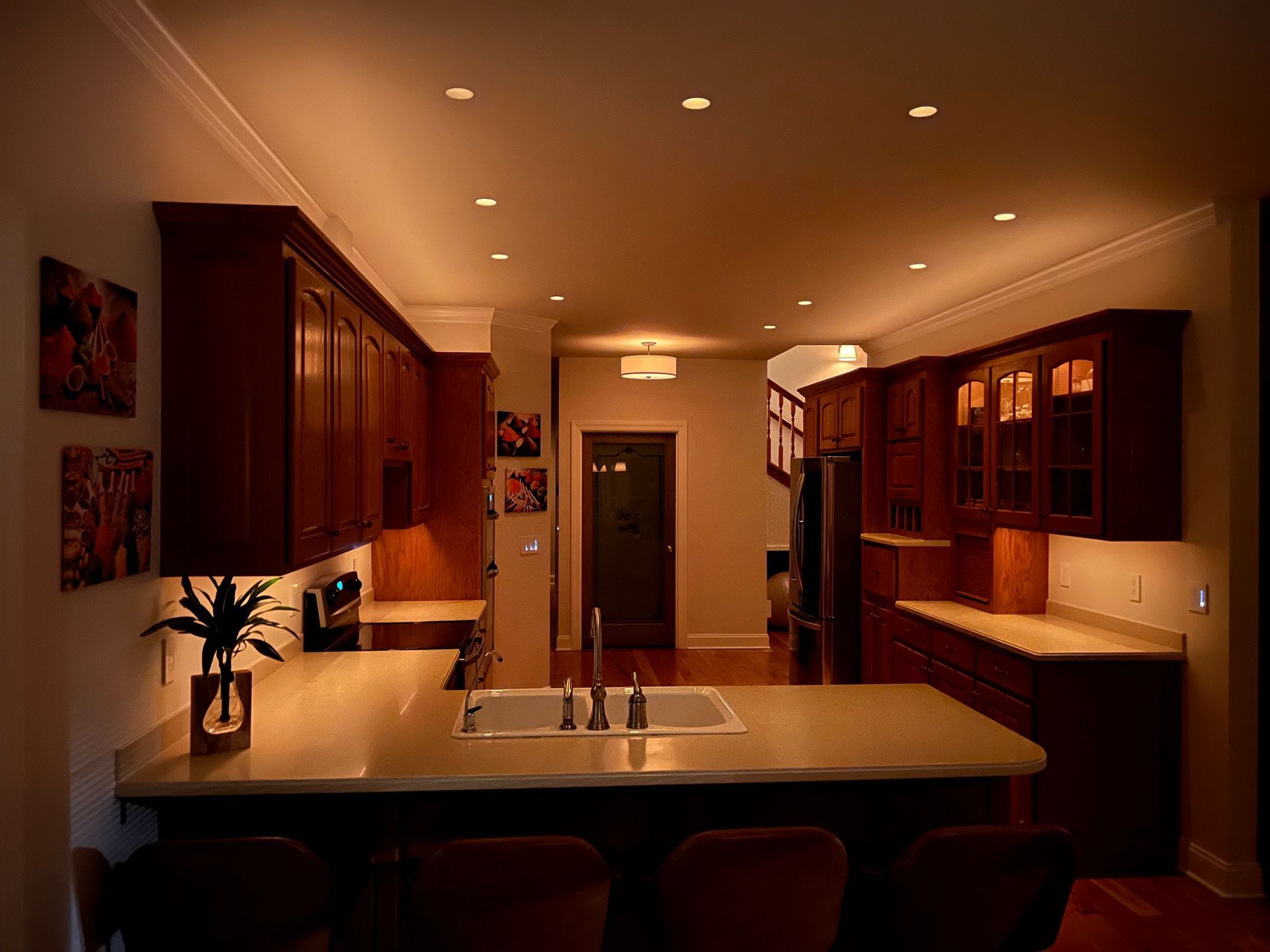 Kitchen with dark wood cabinets, light countertops, recessed lighting, and a view into a hallway.