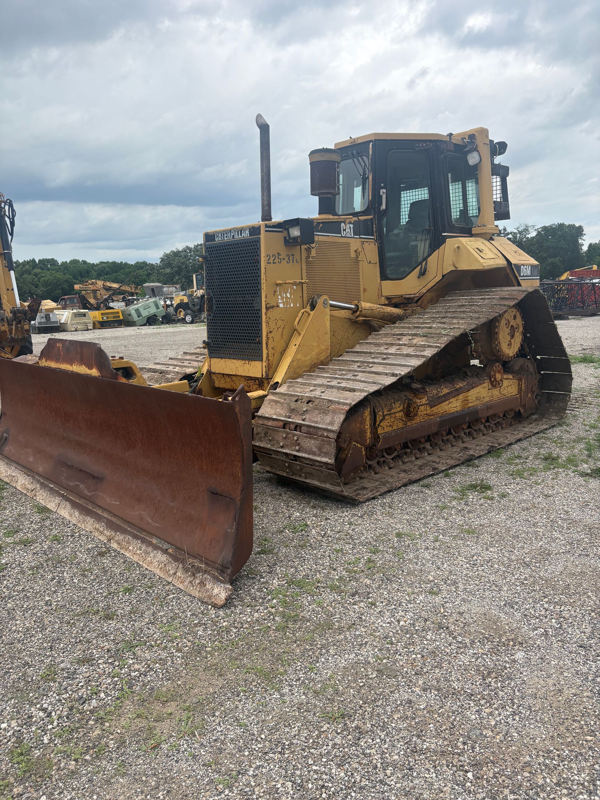 Yellow bulldozer with a large front blade parked on gravel at a construction site