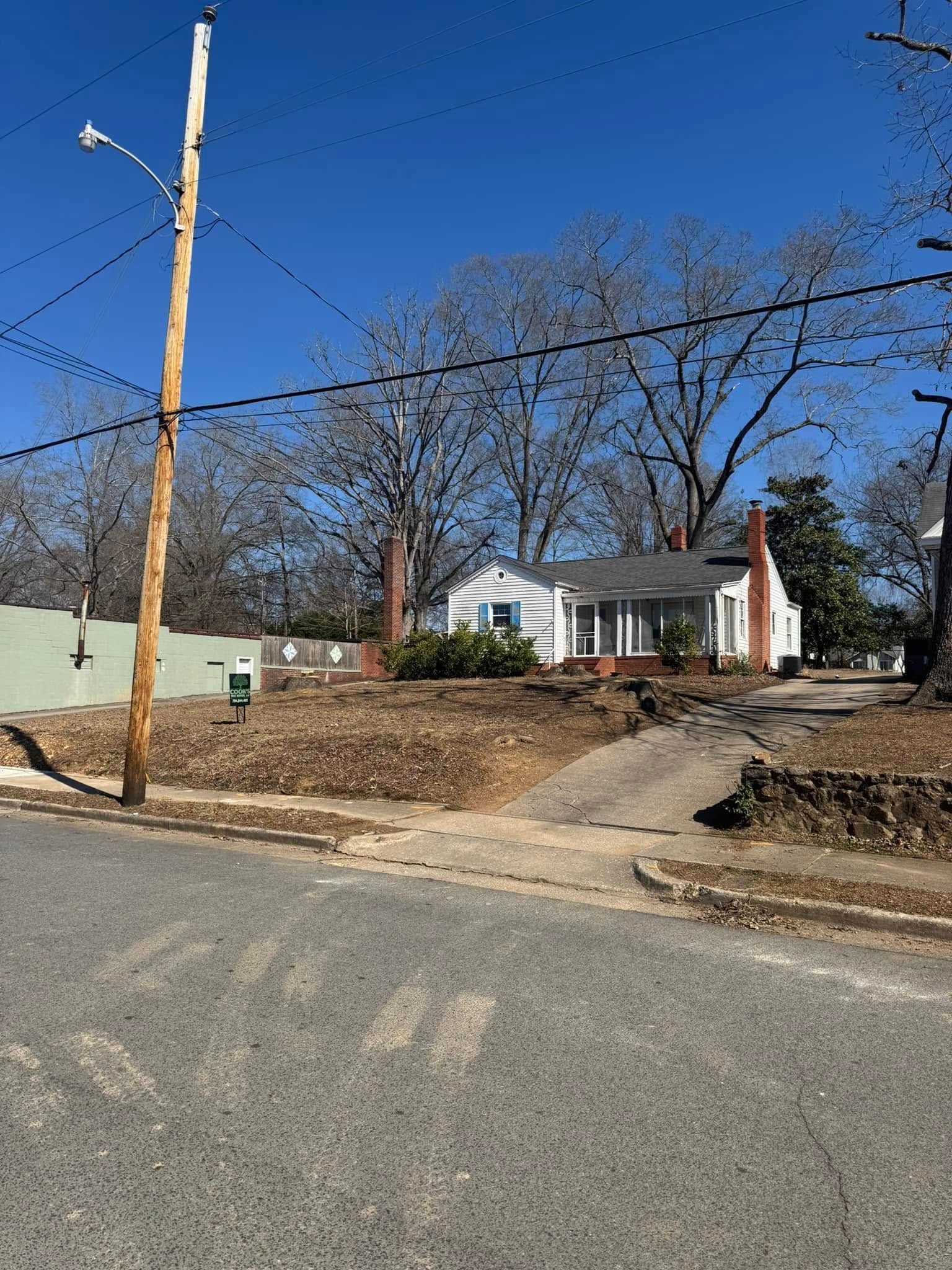 Small white house with red brick chimneys and sidewalk leading up to it, under a clear blue sky.