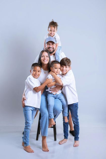 Three people stacked vertically, smiling, with their heads resting on the person's hands directly below them.