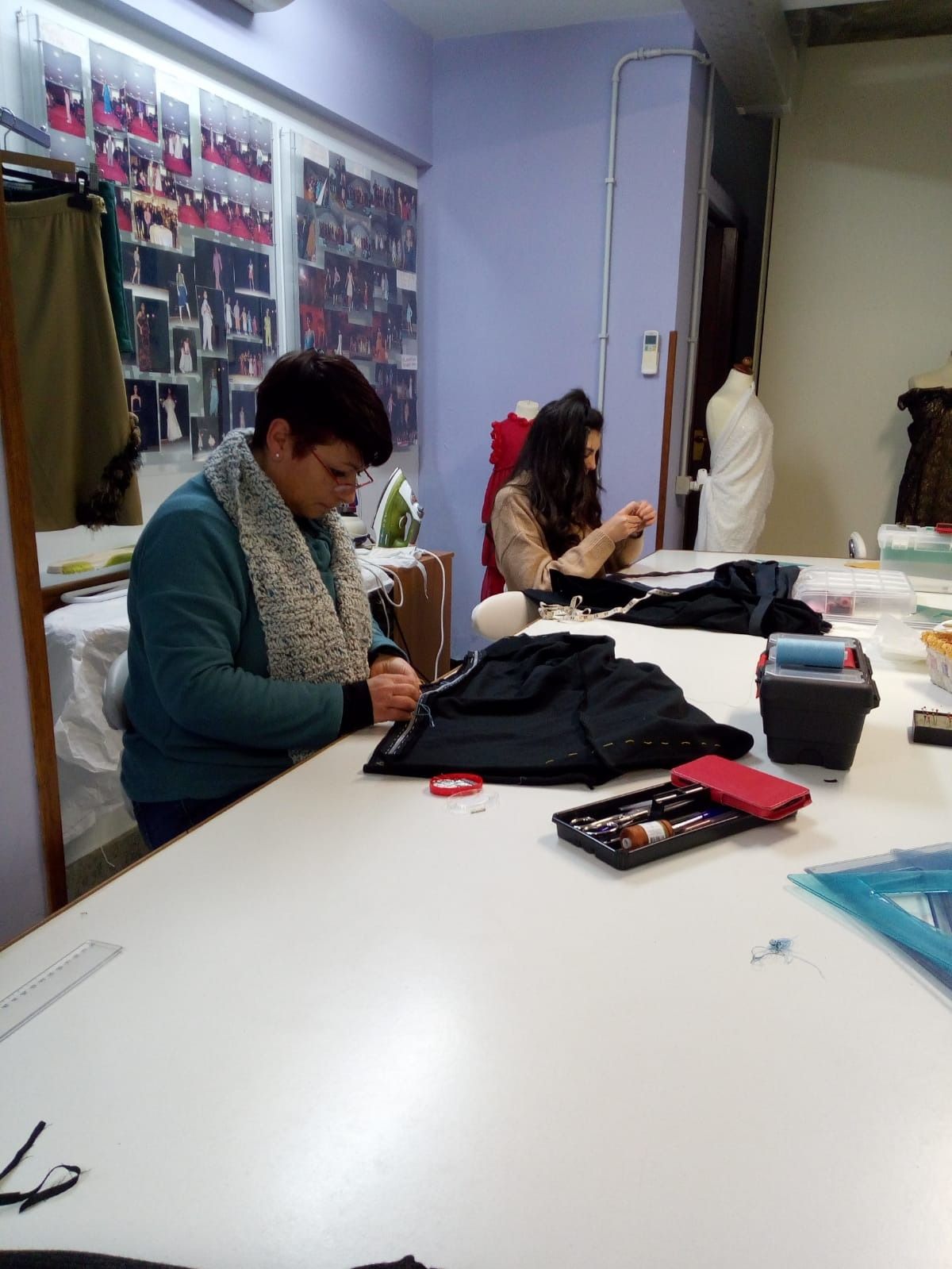 Un uomo è seduto a un tavolo e sta lavorando su un capo di vestiario