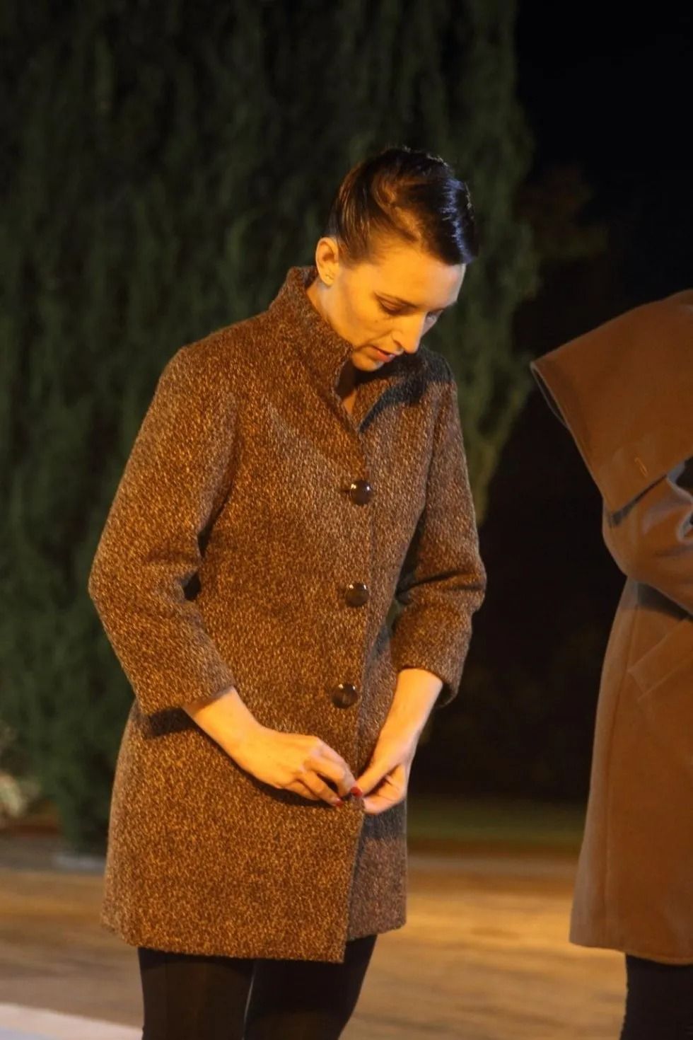 Una donna con un cappotto marrone è in piedi accanto a un uomo con un cappotto marrone.