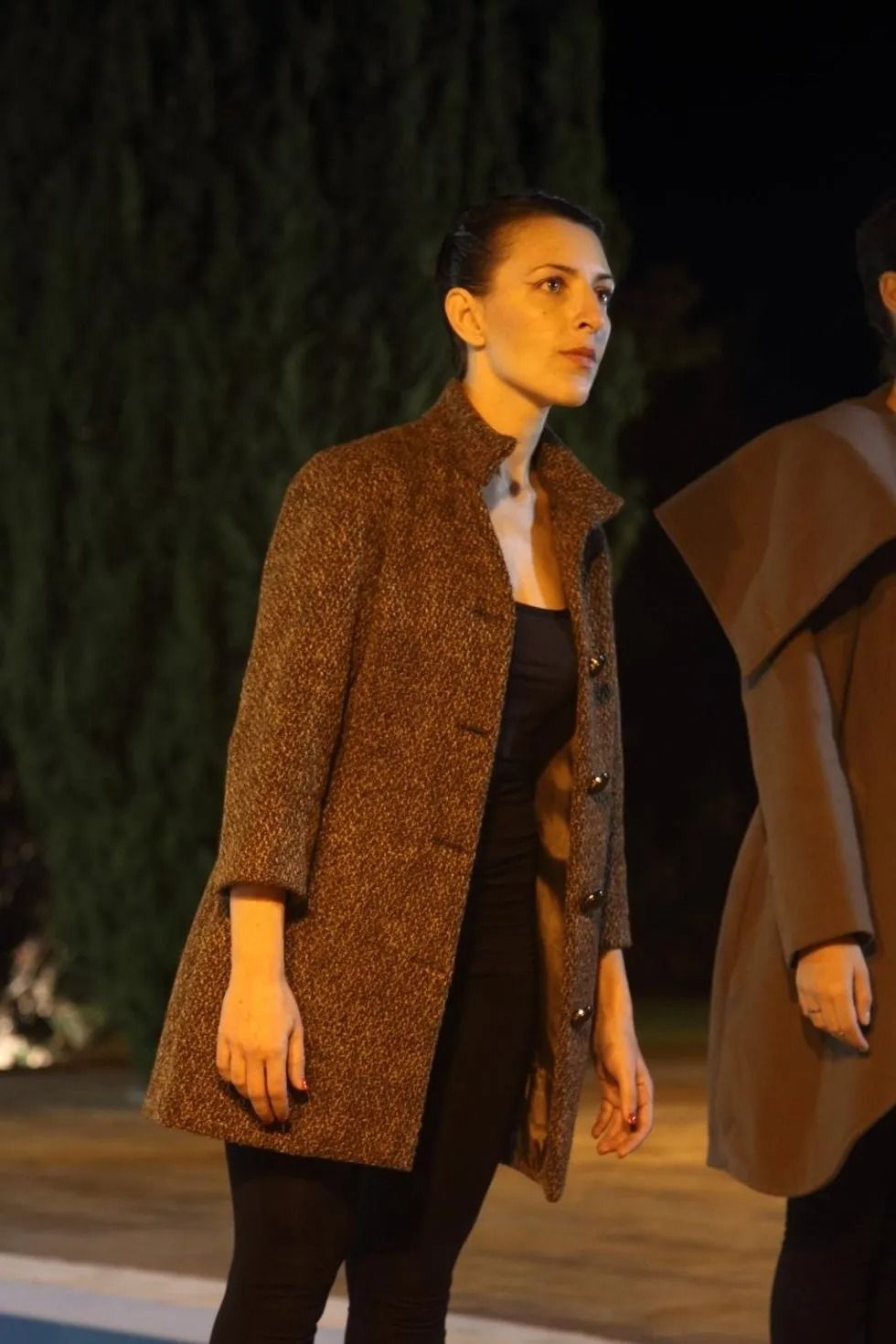 Una donna con un cappotto marrone è in piedi accanto a un'altra donna