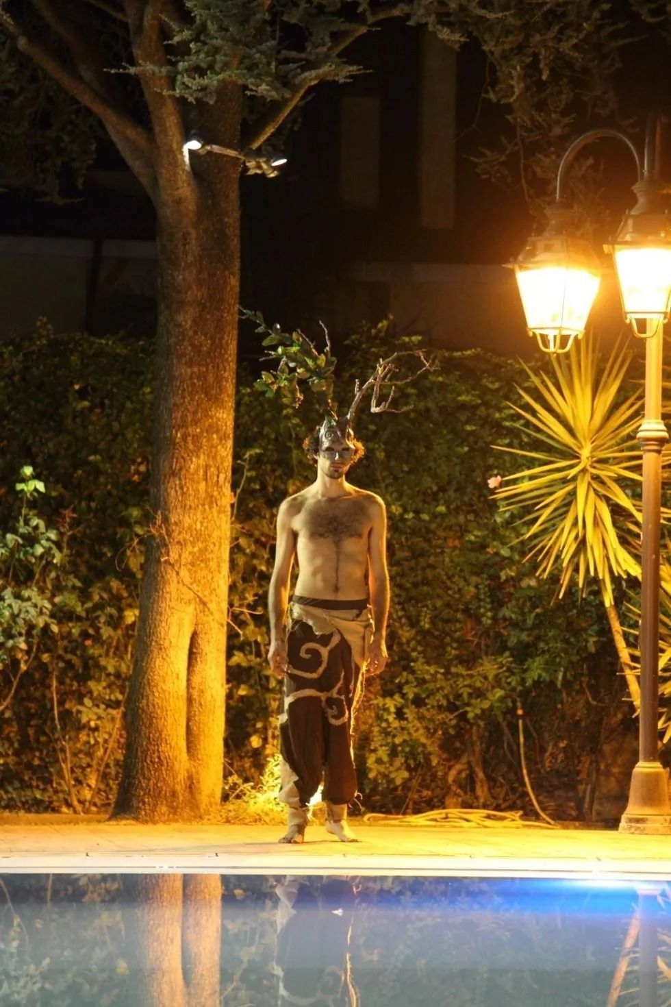 Un uomo a torso nudo in piedi accanto a una piscina di notte