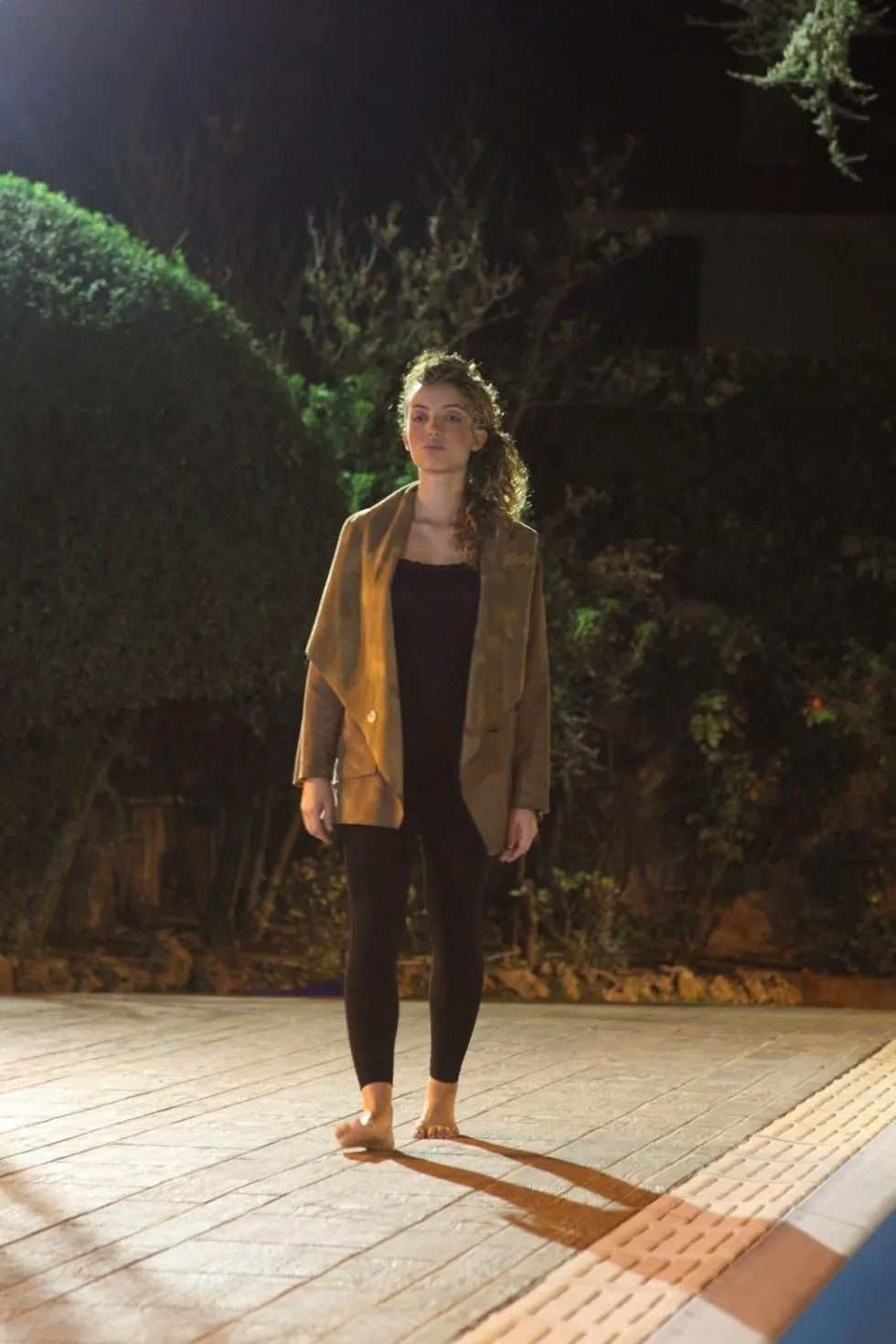 Una donna è in piedi a piedi nudi sul marciapiede di notte.