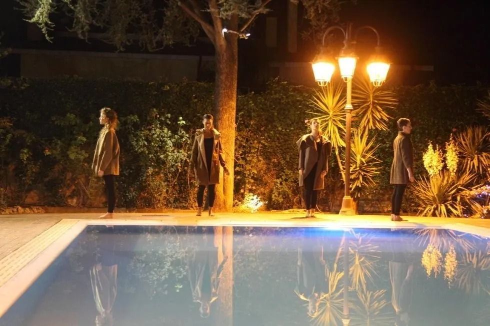 Un gruppo di persone in piedi accanto a una piscina di notte