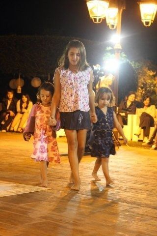 Tre bambine camminano su un pavimento di mattoni tenendosi per mano
