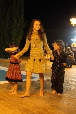 Tre giovani ragazze ballano a piedi nudi davanti a una piscina di notte.