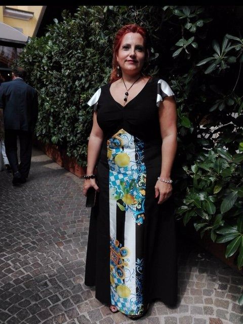 Una donna in abito nero è in piedi su un marciapiede