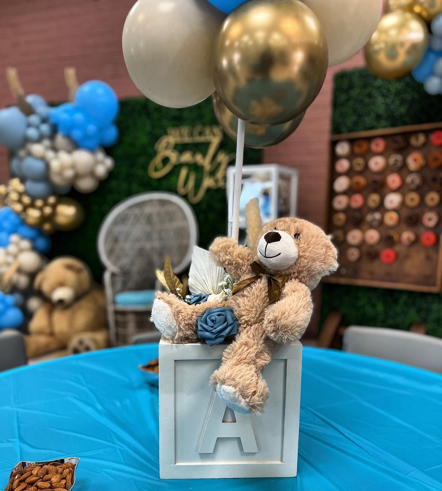 a teddy bear is sitting on top of a block with the letter a on it