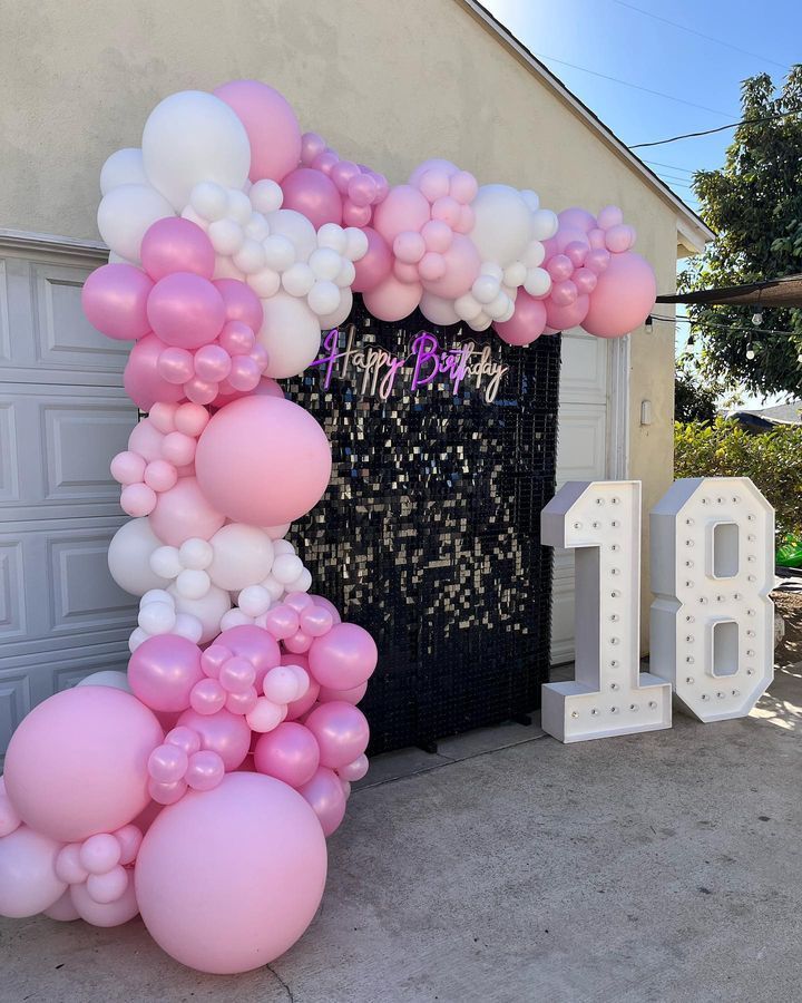 a bunch of pink and white balloons with the number 18 in the background
