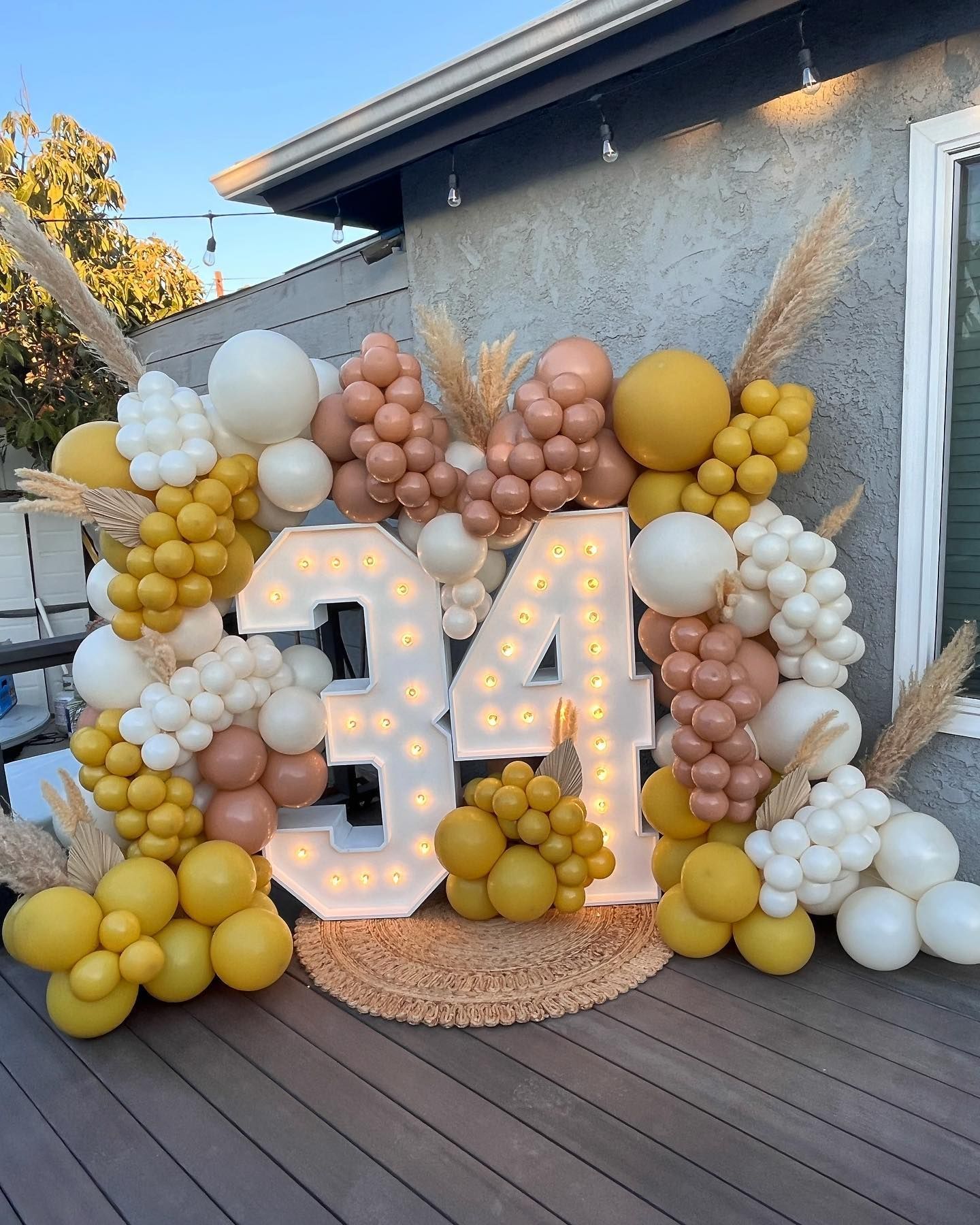 a large number 34 is surrounded by balloons on a deck