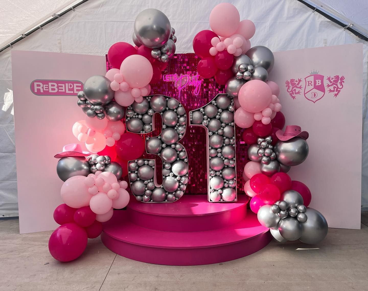 a pink stage is decorated with pink and silver balloons