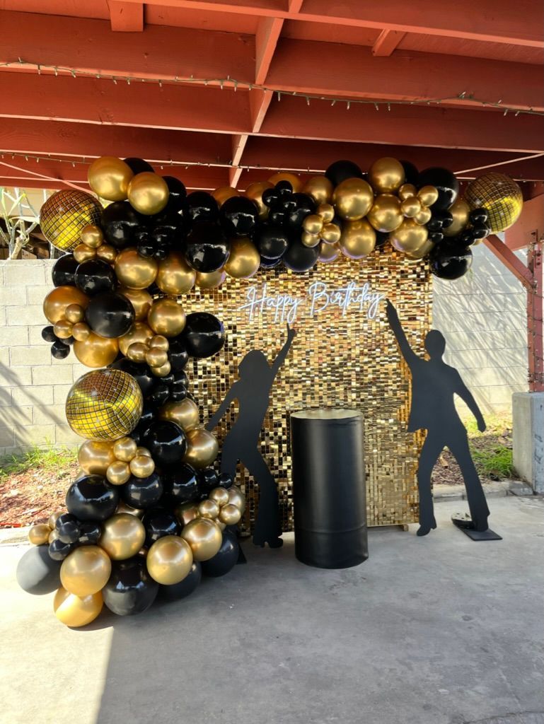 there is a silhouette of a man dancing in front of a wall of balloons .