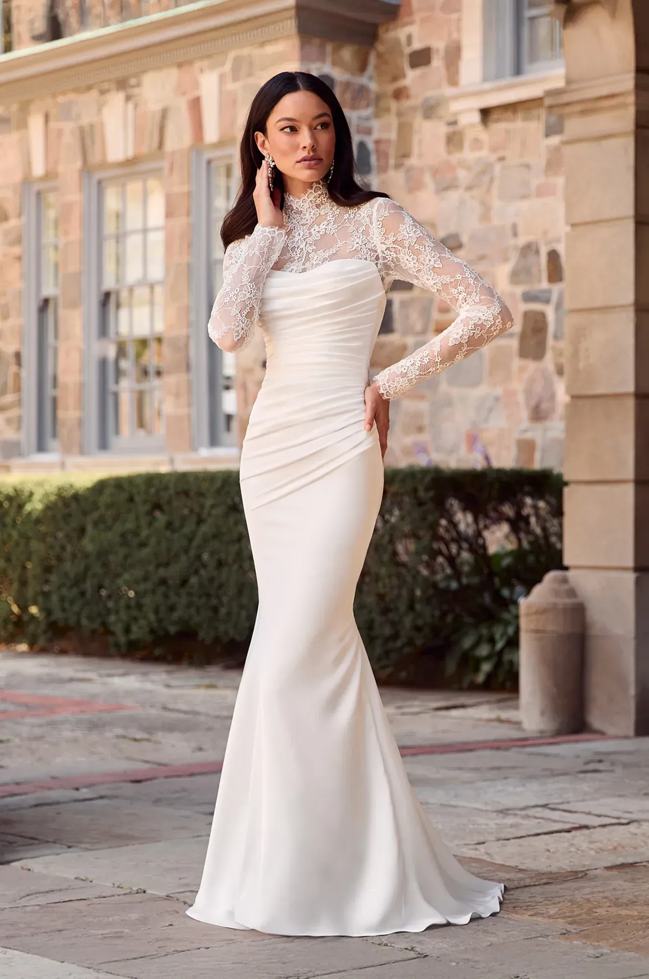 A woman in a white wedding dress is standing in the grass.