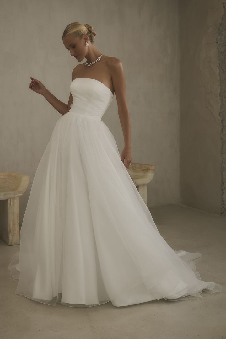 A woman is wearing a white wedding dress with a high slit.