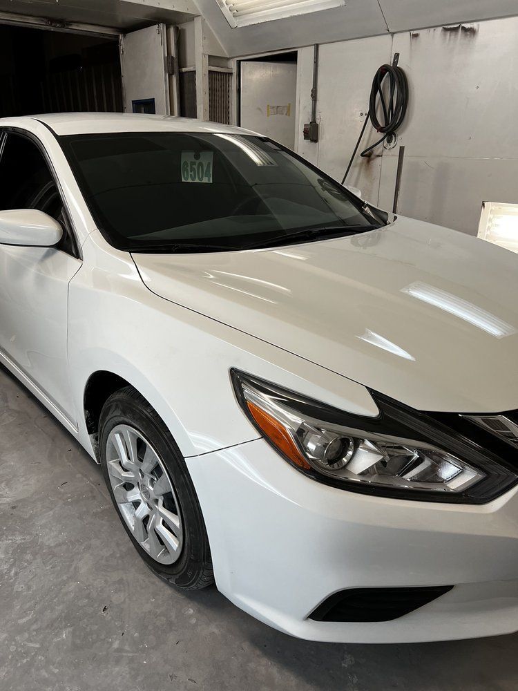 White sedan parked in a garage, front three-quarter view
