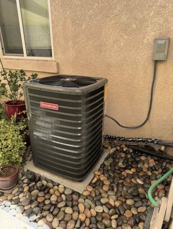 An air conditioner is sitting on the sidewalk next to a wall.