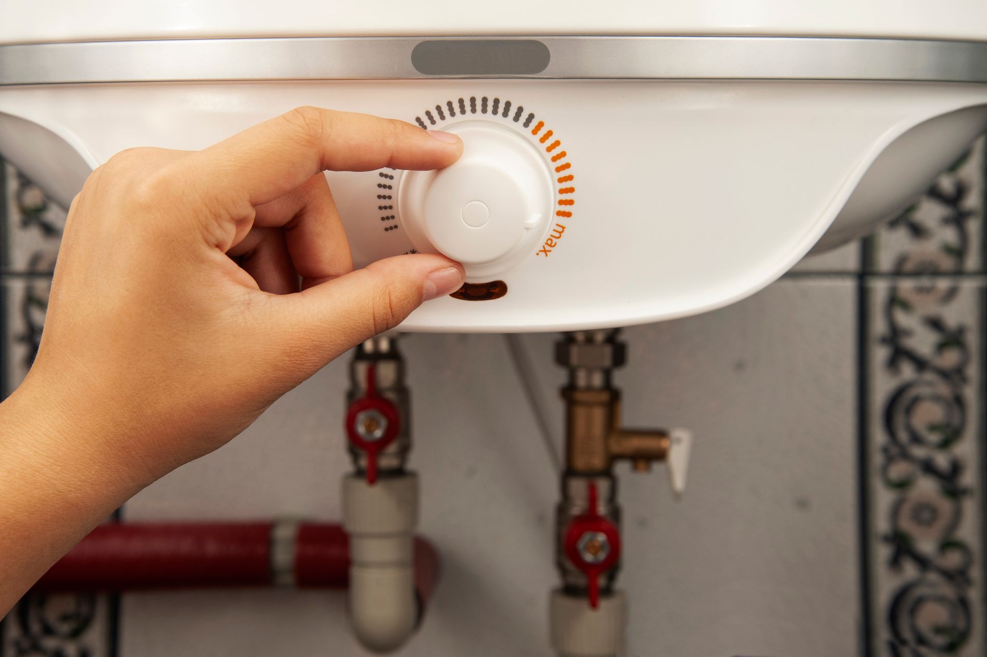 Hand turning temperature dial on a home water heater.
