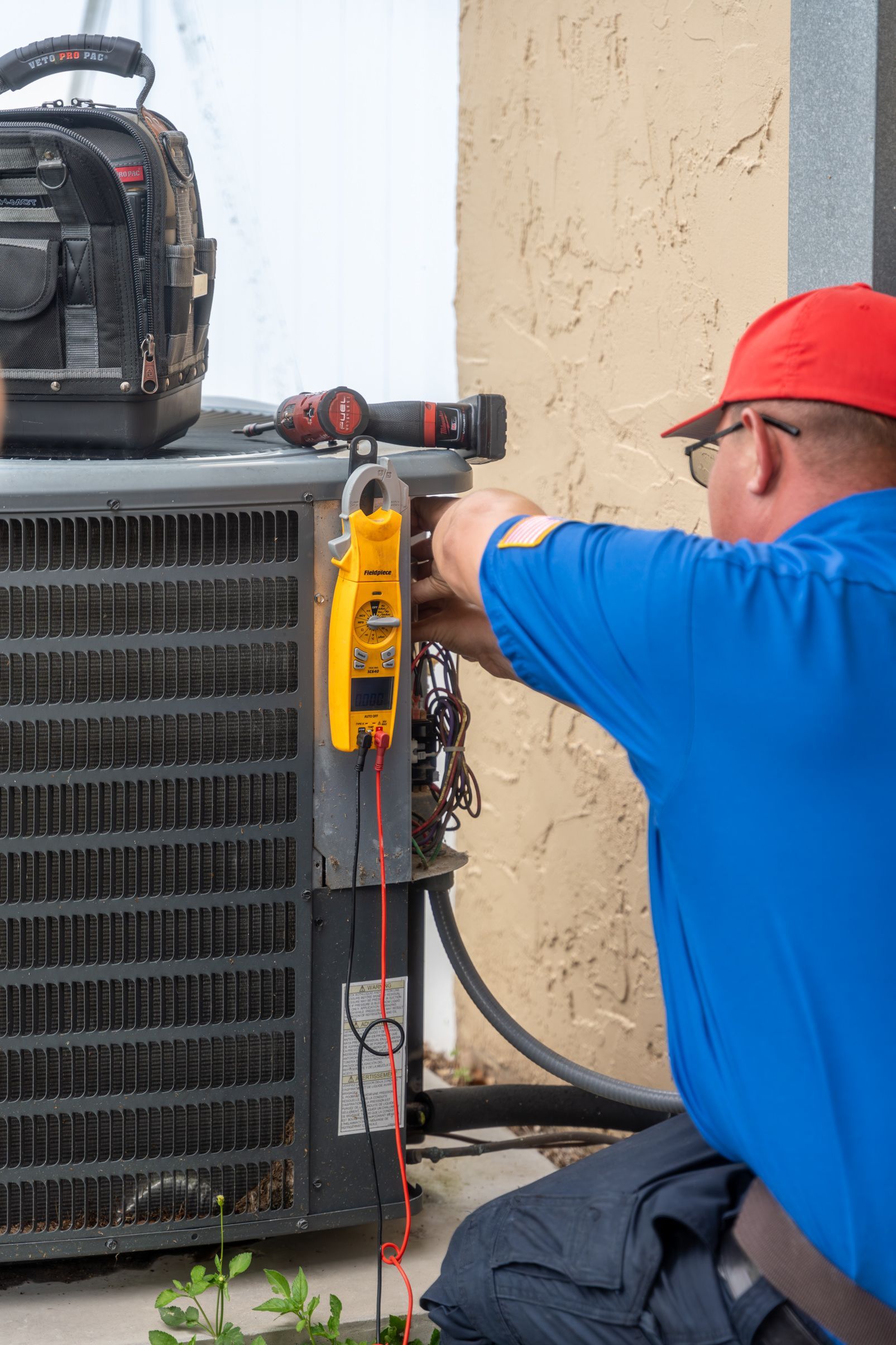 A man is working on an air conditioner outside of a building.