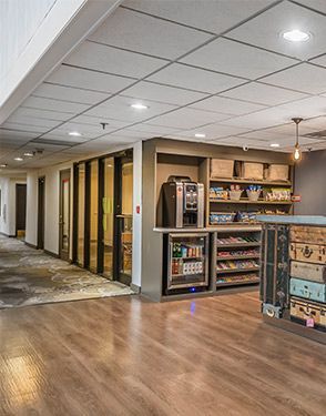 Office hallway with wood flooring, vending machines, and wall shelves under recessed ceiling lights