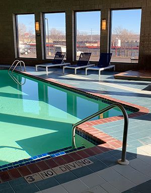 Indoor swimming pool with lounge chairs beside large windows and a no diving sign by the edge