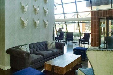 Modern lounge with gray sofa, chairs, and wooden coffee table near large windows