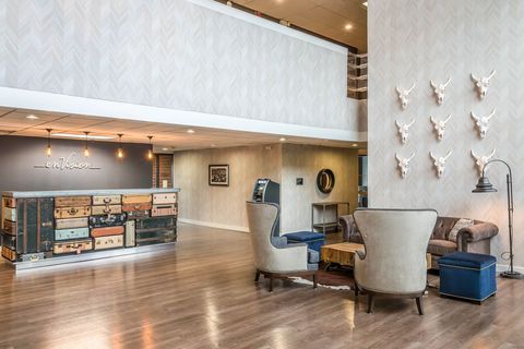 Modern hotel lobby with wood floors, check-in desk, lounge chairs, and wall-mounted decorative accents