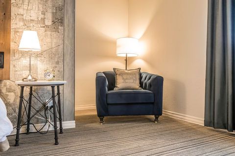 Cozy living room corner with blue armchair, lit lamps, stone accent wall, and gray curtains