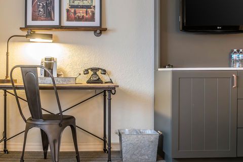 Small desk with lamp, typewriter, chair, and framed art beside a cabinet in a cozy room