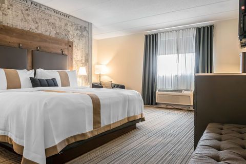 Modern hotel room with two beds, desk lamp, and large window with curtains
