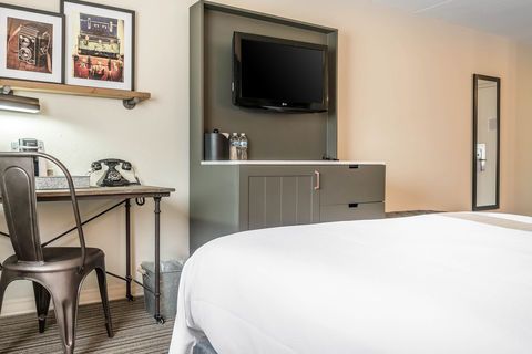 Hotel room with two beds, wall-mounted TV, desk, chair, and cabinet