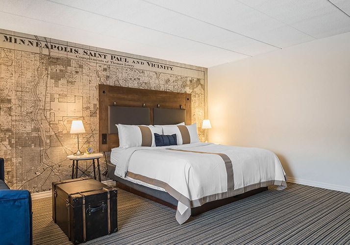 Hotel room with large bed, rustic map headboard, and bedside lamps