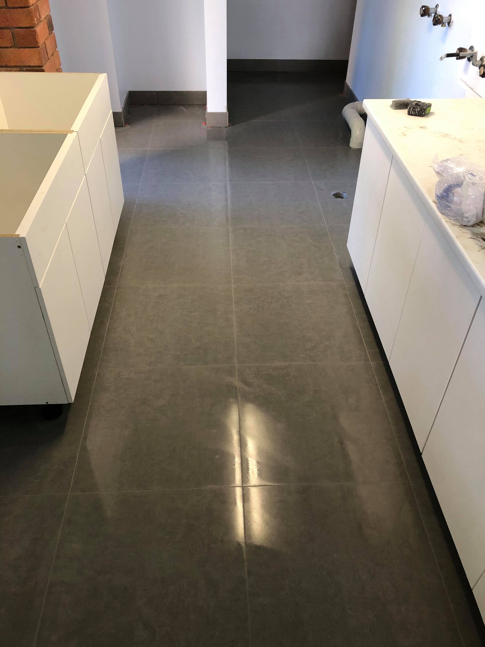 Empty Hallway with Dark Tile Floor and White Cabinets on Both Sides — Midcoast Wall & Floor Tiling in Woolgoolga, NSW